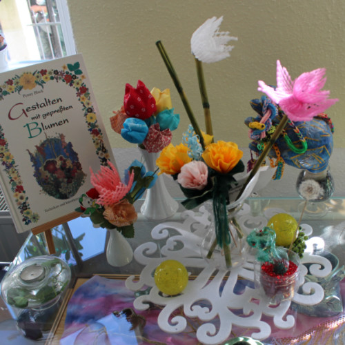 Ein Foto von einem Tisch mit Kunst-Blumen. Die Blumen sind bunt